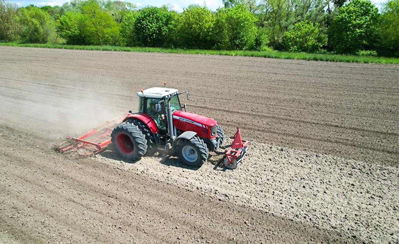 Roter Traktor bei der Bodenbearbeitung auf offenem Ackerland, wobei das automatische Lenksystem NX610 in Aktion zu sehen ist. Bild: CHCNAV